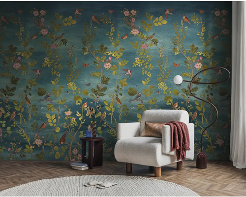 Interieurvoorbeeld met bloemenbehang, fauteuil, staande lamp en bijzettafel voor een stijlvolle woonsfeer.