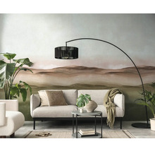 Woonkamer met bank, booglamp en decoratief behang met landschapmotief.