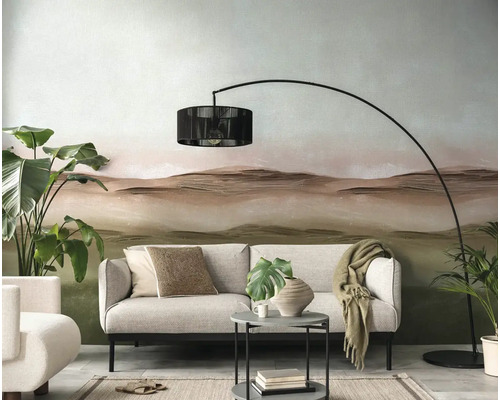 Woonkamer met bank, booglamp en decoratief behang met landschapmotief.