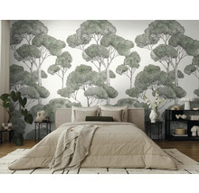 Slaapkamer met een wandbekleding met een boommotief achter een bed.