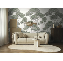 Woonkamer met bank, vloerkleed en behang met boommotief voor een lichte, geordende sfeer