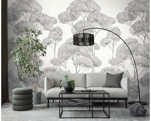 Woonkamer met bank, salontafel, vloerlamp, kamerplant en behang met boommotief