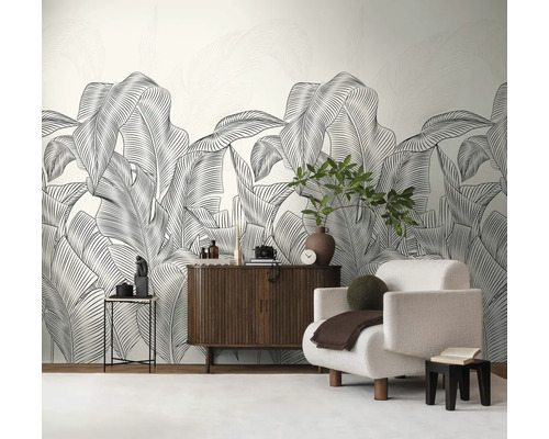 Woonkamer met groot bladerbehang, fauteuil en houten dressoir