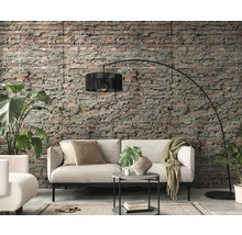 Woonkamer met bank, vloerlamp en bakstenen muur