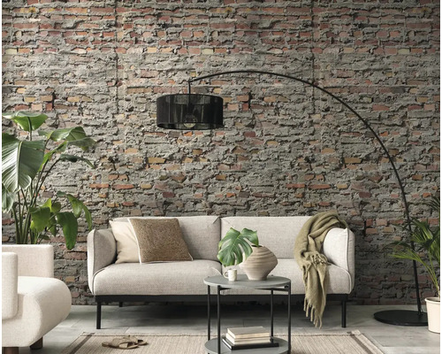 Woonkamer met bank, vloerlamp en bakstenen muur