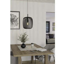 Zwarte metalen hanglamp boven een houten tafel met decoratie