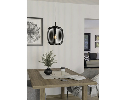 Zwarte metalen hanglamp boven een houten tafel met decoratie