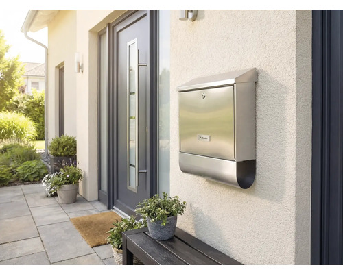 Roestvrijstalen brievenbus aan een huismuur naast een voordeur