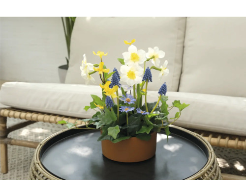 Bloemstuk met narcissen, blauwe druifjes en madeliefjes in een bruine pot op een tafel