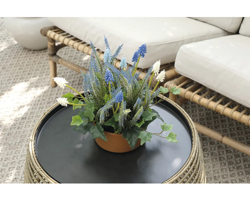 Decoratieve kunstbloemen in een pot op een rotantafel