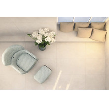 Lichte ruimte met fauteuil, voetenbank, bloemstuk en bank met kussens, van bovenaf genomen