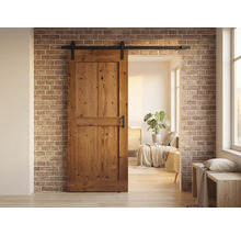 Houten schuifdeur voor een bakstenen muur met een woonruimte op de achtergrond.