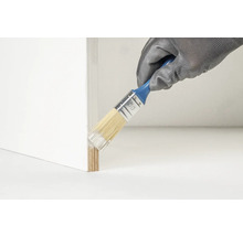 Een persoon draagt handschoenen en schildert een houten rand met een kwast.