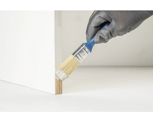 Een persoon draagt handschoenen en schildert een houten rand met een kwast.