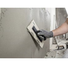 Ambachtsman egaliseert muur met een pleisterspaan en vulmiddel.