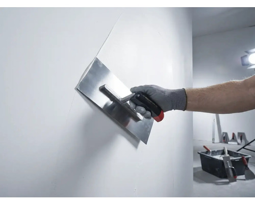 Hand met pleisterspaan bij het gladmaken van een muur