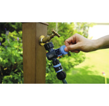 Tuinkraan met waterverdeler en aangesloten tuinslang in gebruik.