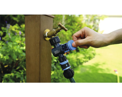 Tuinkraan met waterverdeler en aangesloten tuinslang in gebruik.