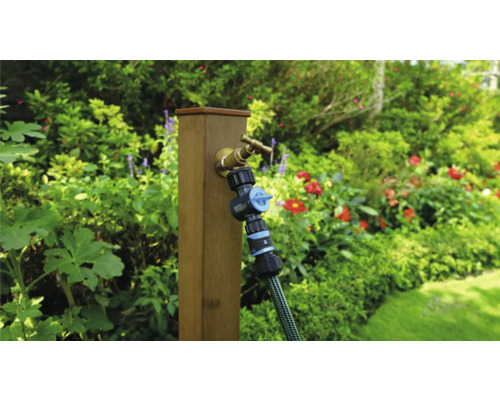 Tuinscene met waterkraan, verdeler en slang op een houten paal