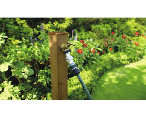 Tuinscene met kraan en tuinslang aan een houten paal