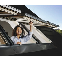 Vrouw opent dakraam voor daglicht en ventilatie