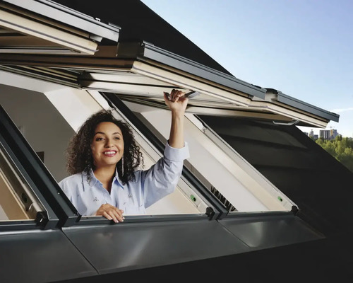 Vrouw opent dakraam voor daglicht en ventilatie