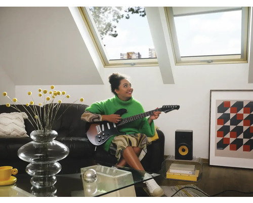 Vrouw speelt gitaar in een lichte woonkamer met dakramen