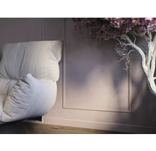 Detailopname van een fauteuil met kussens en decoratieve boom in interieur.