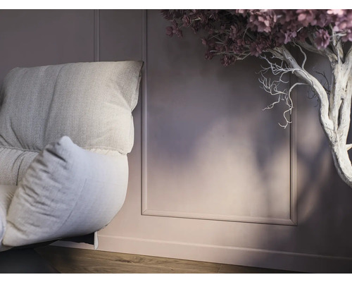Detailopname van een fauteuil met kussens en decoratieve boom in interieur.