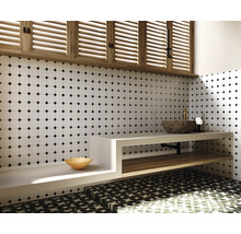 Badkamer met witte tegelwand met zwart stippenpatroon, wastafel met stenen wasbak en houten plank