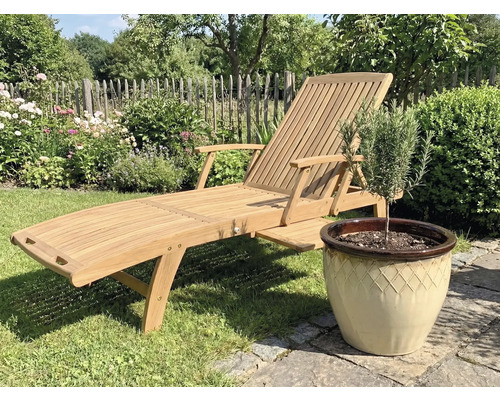 Houten tuinligstoel naast een pot met plant in de tuin