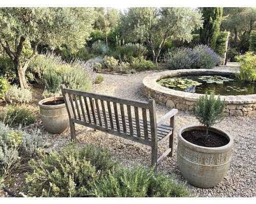 Tuinscene met houten bank, plantenbakken en vijver