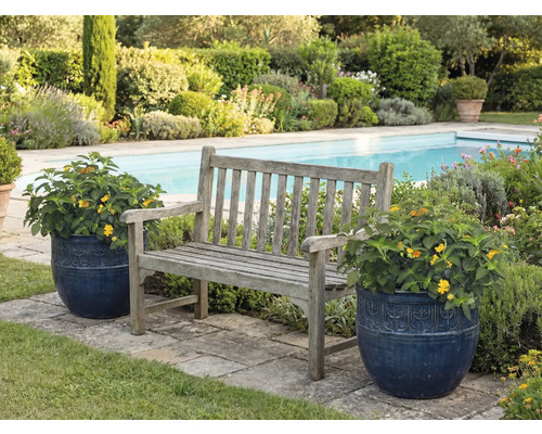 Tuin scène met houten bank en bloempotten naast een zwembad