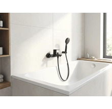 Moderne badkamer met wit ligbad en zwarte kraan met handdouche.