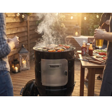 Rookgrill met vlees en groenten op het grillrooster tijdens een barbecue in de tuin.