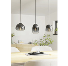 Drie glazen hanglampen boven een houten tafel in een lichte ruimte