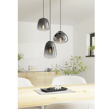 Drie glazen hanglampen boven een houten tafel in een lichte kamer