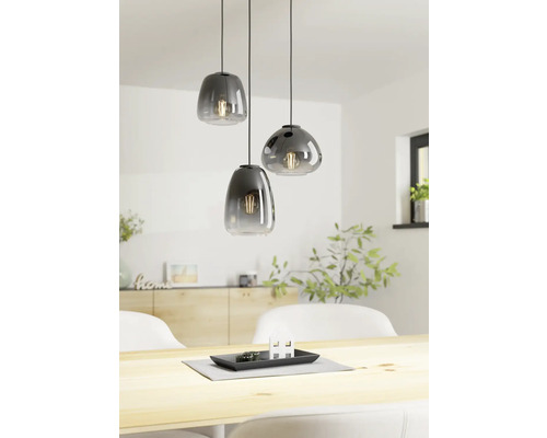 Drie glazen hanglampen boven een houten tafel in een lichte kamer