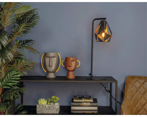 Decoratieve scène met tafellamp, siergezichten en potplanten op een plank.