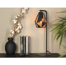 Decoratieve scène met een zwarte tafellamp, een vaas met katoentakken en boeken