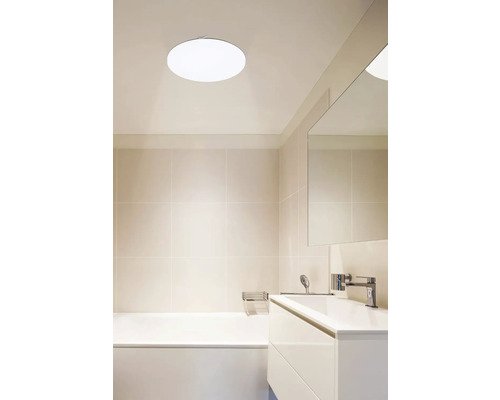 Lichte badkamer met bad, wastafel en ronde plafondlamp