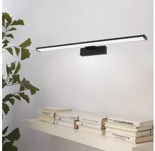 Wandlamp met strak design boven een plank met boeken en een plant.