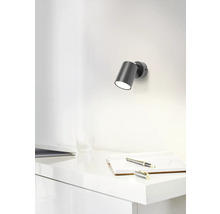 Scene met een wandlamp boven een bureau met notitieboek en pen