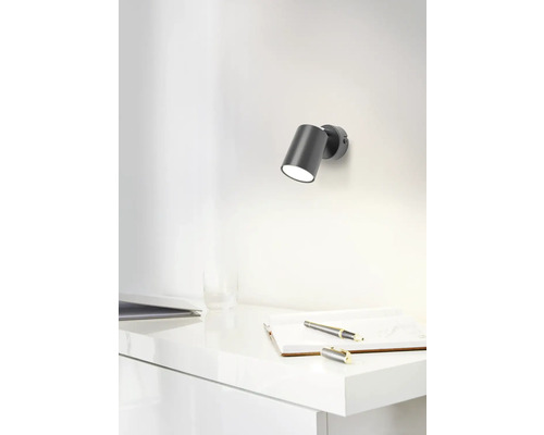 Scene met een wandlamp boven een bureau met notitieboek en pen