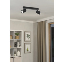 Zwarte plafondlamp met twee spots in een heldere kamer.