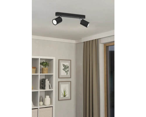 Zwarte plafondlamp met twee spots in een heldere kamer.
