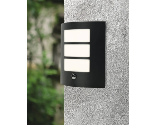 Zwarte wandlamp met bewegingsmelder en drie rechthoekige lichtvensters aan een muur.