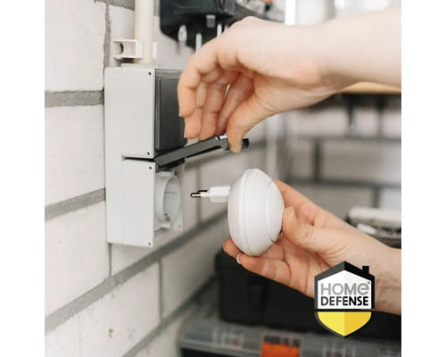 Iemand steekt een stekker in een stopcontact. Home Defense Logo