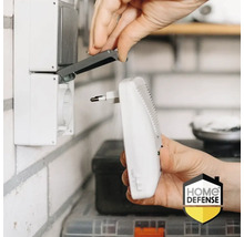 Iemand steekt een elektrische insectenverdelger in een stopcontact. Home Defense logo.