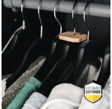 Zwarte kledinghangers met cederhouten stuk aan de haak en hangende kleding aan een kledingroede